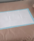 Straight Up Reliable Disposable Underpads For Adults Super Absorbent Leak Proof Incontinence Bed Pads on a bed surface.