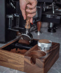 Hand using portafilter with wood handle on Straight Up Heavy Duty Wooden Espresso Knock Box Tamping Station.