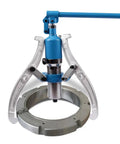 Beefy Hydraulic Gear Puller Kit With 2 And 3 Jaw Convertible Heads, shown with adjustable jaws around a circular part.