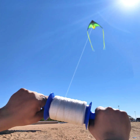 Flying kite with Kite Spool Reel Winder With Grip String Handles, 600 Feet Twisted Polyester Line, held by hands on a sunny day.