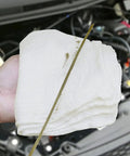 Hand holding 100 Percent Cotton Shop Towels Pack of 150 Reusable Absorbent Cleaning Rags 14x14 Inches Tough as Nails near car engine