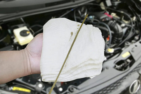 Hand holding 100 Percent Cotton Shop Towels Pack of 150 Reusable Absorbent Cleaning Rags 14x14 Inches Tough as Nails near car engine