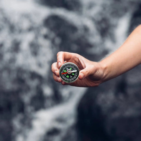 Hand holding Trail Ready High Precision Horizontal Bubble Compass Portable Circular Navigation Tool for outdoor travel.