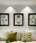 Top Shelf 14 Pack Recessed Led Ceiling Lights With Three Color Dimming And Slick Copper Trim For Modern Living Rooms Energy Saving Ambient Glow Quick Install Solid Home Fixtures illuminating framed botanical art above a light sofa.