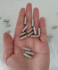No Sweat Heavy Duty Metal Shelf Pegs 50 Pack Five Millimeter Cylinder Pins in a hand, showcasing iron pins for cabinet support.