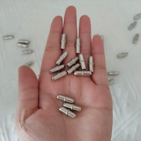 No Sweat Heavy Duty Metal Shelf Pegs 50 Pack Five Millimeter Cylinder Pins in a hand, showcasing iron pins for cabinet support.