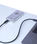 USB4 NVMe Enclosure With Active Cooling Fan And Solid Aluminum M.2 SSD Case connected to laptop via USB cable.