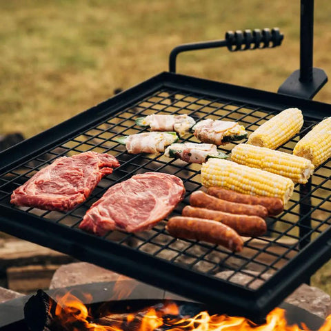 Adjustable Swivel Grill Grate For Open Fire Cooking With Spike Pole Steel Mesh Wire Grate showing meats and corn on grill.