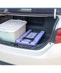 Heavy Duty Folding Trolley Cart With Slick Nylon Rollers And Sturdy Aluminum Frame in car trunk beside storage bin.