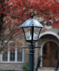 Baytown II Outdoor Solar Lamp Post with EZ Anchor Kit, Black Finish in autumn garden, showing dusk to dawn operation.
