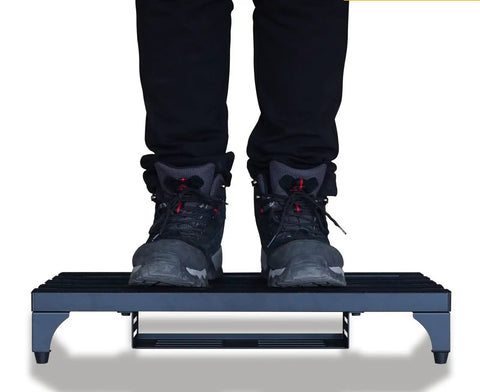 Bottom view of person standing on 22 X 12.5 Inch Aluminum Guitar Pedal Board With Power Supply Tray Carry Bag And Mounting Tapes Included Black Portable Lightweight For Gigging Musicians showcasing its strength and stability.