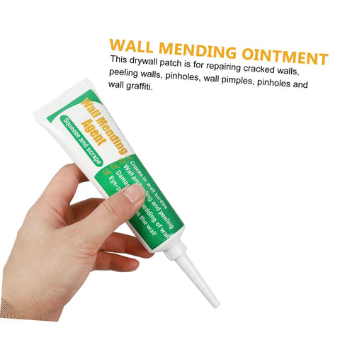 Hand holding wall mending cream tube, labeled 'Wall Mending Agent,' from Two Pack Wall Mending Repair Cream With Scraper Quick Crack Fix For Home And Office DIY Patch Paste Easy To Use Self Adhesive Wall Hole Repair Paste To Fix Cracks And Holes Fast