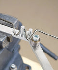 Penitue Manual Wire Bending Tool For Desktop shaping a metal rod in a vice, showcasing its sturdy ferroalloy steel design.