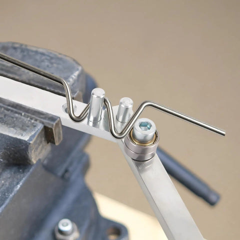 Penitue Manual Wire Bending Tool For Desktop shaping a metal rod in a vice, showcasing its sturdy ferroalloy steel design.