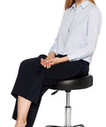 Person seated on Drafting Stool On Wheels With Adjustable Height, 360 Degree Swivel, Black Bonded Leather, Chrome Base, Heavy Duty Casters.