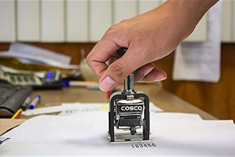 Top Shelf Six Wheel Automatic Numbering Machine Self Inking Office Stamp with hand stamping clear serial numbers on paper.