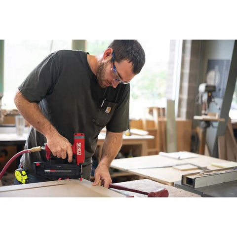 Pro Grade Pneumatic Pin Nailer For Cabinet Trim And Fine Woodworking ships ready, used by a man in a workshop.