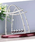 Newton's Cradle Pendulum Dynamics Learning Kit for Hands-On Education and Large Desk Decor, silver structure on red base.