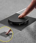 Drop Down Square Pop Up Floor Drain With Matte Black Chrome Cap and Odor Locking Grille for Bathrooms, user pressing the cap.