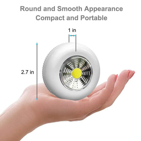 Person holding Six Pack Portable LED Puck Tap Lights Battery Operated Night Lights for cabinets and more, size 2.7 inches.