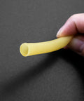Yellow latex rubber tubing held between fingers; flexible medical/lab tubing.