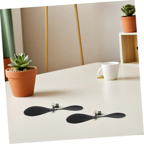 10 Pack RC Airplane Propeller Set With 6x4mm Hole Diameter showing two black plastic blades on a table with plants