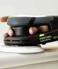 Topshelf Random Orbit Sander With Stepless Speed Control, ergonomic design in use on wooden surface for smooth finishing.
