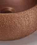Close-up of the textured rose gold ceramic surface of USZWBY Vessel Sinks Bathroom Sink European Round Rose Gold Home Hotel Above Counter Basin.