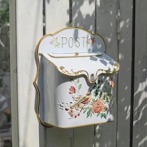 Decorative white wall mount mailbox with floral design, nostalgic English cottage garden decor for home exterior.