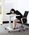 Slick Electric Height Adjustable Lectern With Smooth Roll Wheels For Boardroom Church Or Lecture Hall Speaking Ergonomic Mobile Standing Podium Designed For All Day Grind And Zero Sweat Operation with a user resting on a desk.