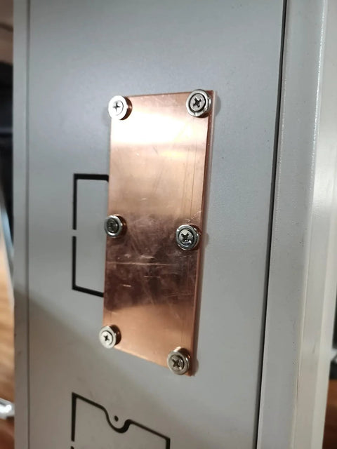 Close-up of magnetic copper spoon backer attached to a welding surface featuring a smooth copper panel and secure screw mount.