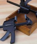 Six Piece Easy To Use One Handed Trigger Clamp Set With Four Inch And Six Inch Clamps In Black And Grey on wooden surface