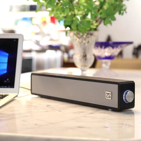 Vintage Wooden Mini PC Sound Bar With 3.5mm Aux, USB Powered Desktop Speakers For Monitor, Laptop, And Tablet Retro Style Delivers Crisp Stereo 2x5W Audio placed beside a laptop on a marble table.