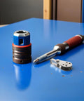 Tools on blue surface including stainless steel cable pulley, drill attachment, and handle, not the Stainless Steel Cable Pulley Blocks Set Of 4 With Bearings Beefy Heavy Duty Rope Pulleys For Kayak Sailing And Boating Gear Marine Use Outdoor Rugged Hardware.