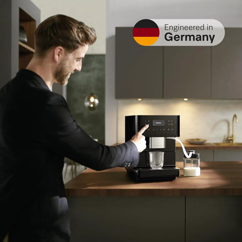 Sleek Fully Automatic Coffee And Espresso Machine With Silent Steel Grinding Chamber For Killer Cup Creations and Rich Silky Milk Foam For Serious Home Baristas, operated by a man in a kitchen.