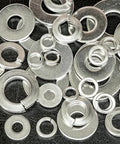 Close-up of assorted stainless steel lock and flat washers (various sizes) scattered metal fasteners.