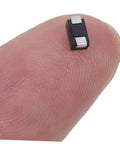 Hella Reliable 100 Piece SMD Rectifier Diode Pack Built Tough For High Voltage Circuits, small diode shown on fingertip.