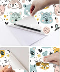 Slick Pastel Woodland Peel And Stick Wallpaper With Cute Animal Head Prints being applied with a pen and smooth tool for neat installation.