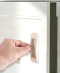 Hand installing 4 Pcs Self Stick Instant Cabinet Drawer Handles Adhesive No Drill Mounting on white cabinet door.