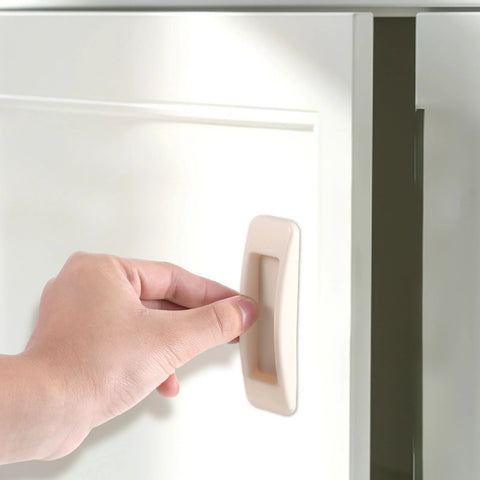 Hand installing 4 Pcs Self Stick Instant Cabinet Drawer Handles Adhesive No Drill Mounting on white cabinet door.