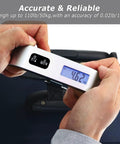 Hands holding Hassle Free Travel Luggage Scale Portable Digital Hanging Baggage Scale With 110 Lb Capacity Lightweight Suitcase Weight Scale Battery Included Silver.