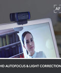 Pro Grade Full HD 1080P Webcam With Crisp Dual Mics And Snappy Auto Focus mounted on a laptop with HD autofocus and a light correction feature.