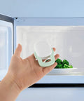 Hand holding Four Pack Childproof Oven Safety Locks For Cabinets And Microwaves Durable ABS Kitchen Locks near microwave