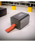 Slick Mini Thermal Label Printer Featuring Wireless Wifi And Usb Hookup As A Total Game Changer For Rapid Shipping DIY Crafting At Home Or Side Hustle Barcode Tape Maker printing a red label.