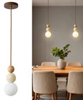 Wabi Sabi Travertine Pendant Light with Wood Ball & Milk Glass Shade over a dining table with natural decor.