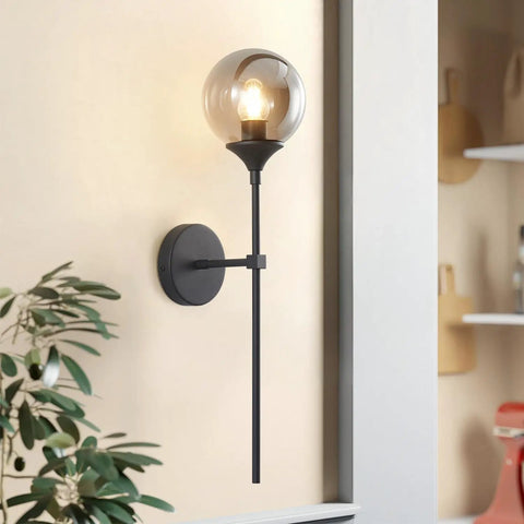 Sleek Smoke Grey Glass Globe Wall Sconce In Black Matte Finish With Slim Long Wall Mount Lamp Vintage Industrial Vibe For Hallway Stairs And Bathroom Modern Farmhouse Lighting against wall.
