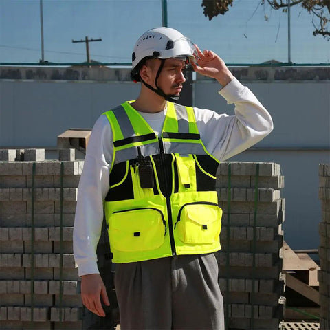 High Visibility Reflective Safety Vest With Heavy Duty Construction And Plenty Of Pocket Space For Tools On Any Job Site Hella Bright Orange Unisex Work Vest In Three X Large Size worn by worker with helmet in construction area.