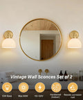 BELVM Vintage Milk Glass Wall Sconce Set of 2 - Gold Bathroom Wall Lights beside a round mirror in a stylish bathroom.