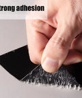 Close-up of hand peeling 4 in x 5 ft Flexible Rubberized Waterproof Tape 4 Inch 5 Foot Patch And Seal For Leaks Works Underwater Like A Boss Indoor Outdoor Use Roof Plumbing Pool And RV Repairs Black