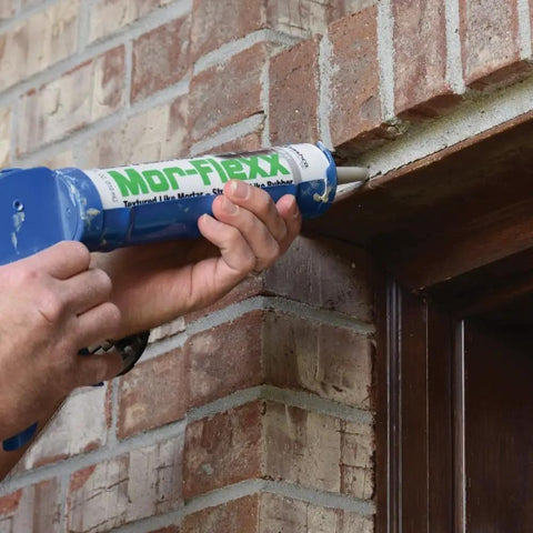 Applying Mor-Flexx Gray Acrylic Latex Caulk For Mortar, Stucco, And Grout Repair on outdoor brick wall with caulking gun.